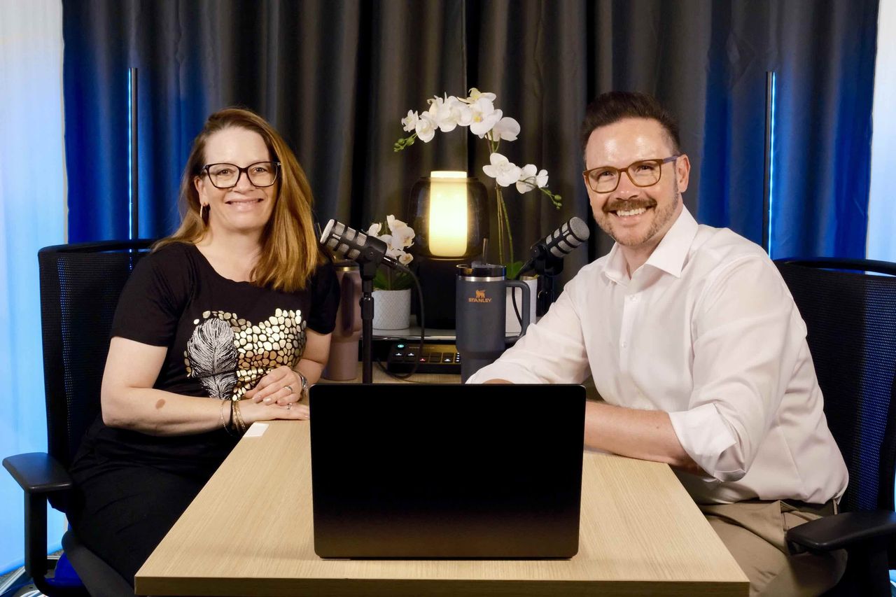 Foto: Janine und Oliver sitzen lachend nebeneinander am Studiotisch, vor ihnen ein Laptop und zwei Mikrofone.